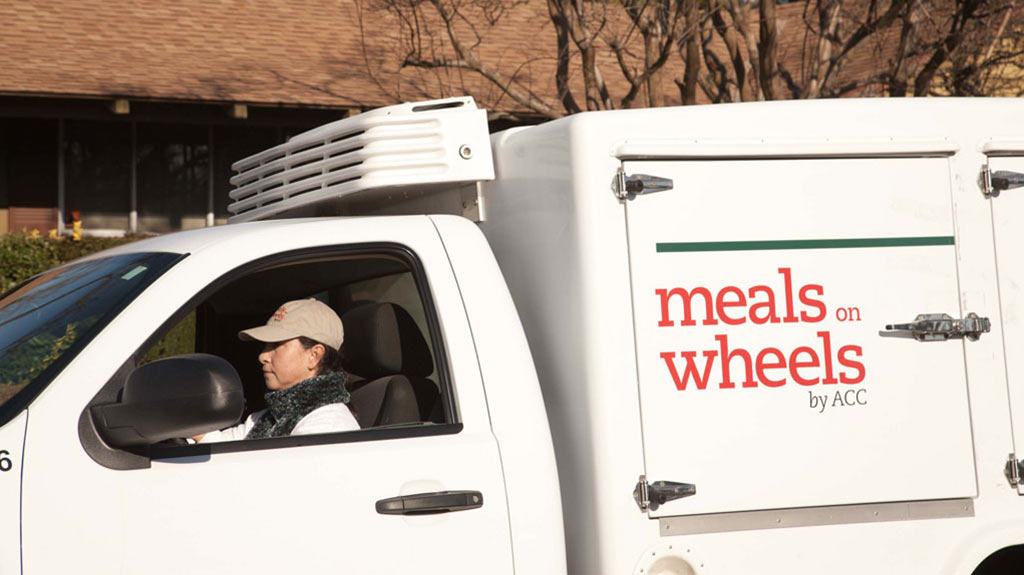 an image of a woman in a delivery truck delivering food to individuals
