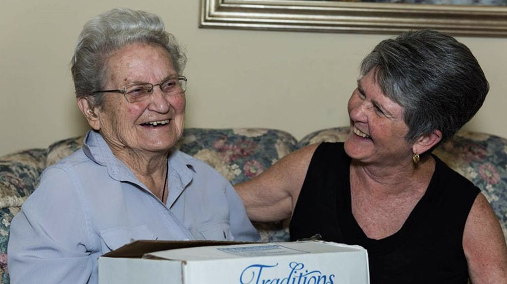 an image of two older women sitting together on a couch and laughing together
